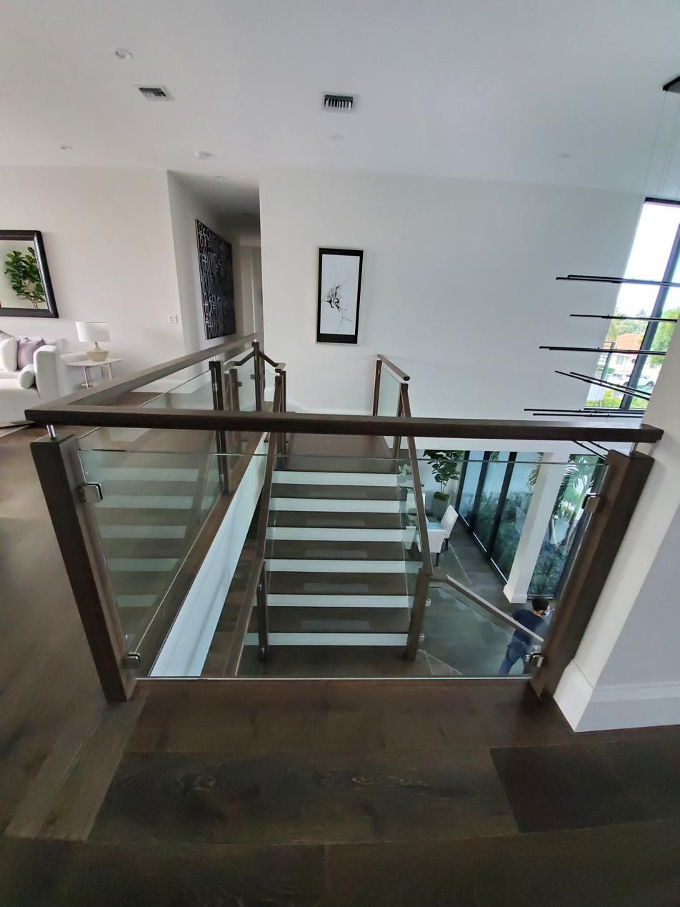 Staircase with glass panel railing and wood handrail