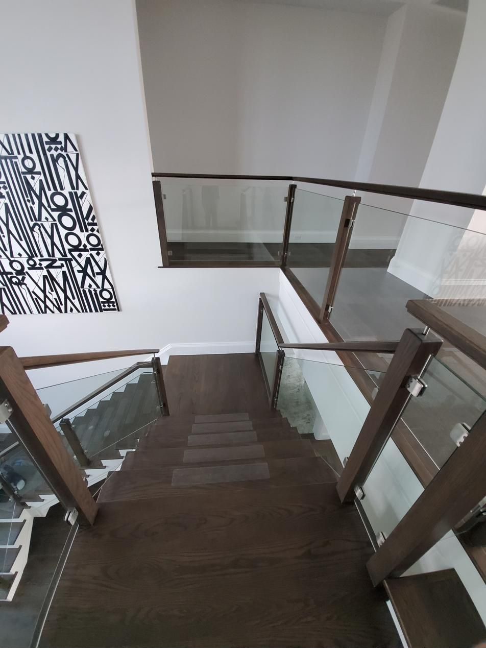Glass panel railing with dark wood handrail