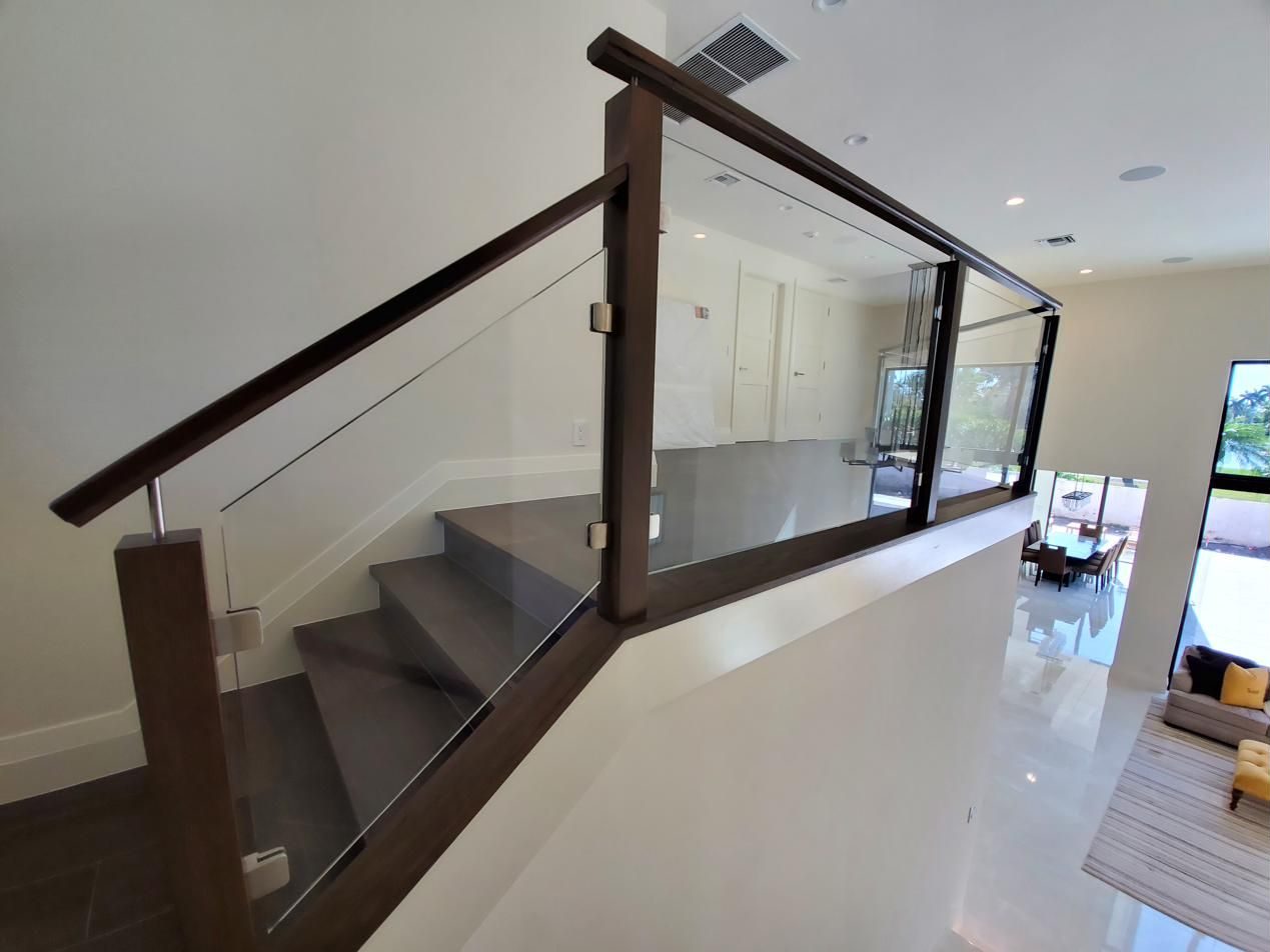 Staircase with glass railing and dark wood cap