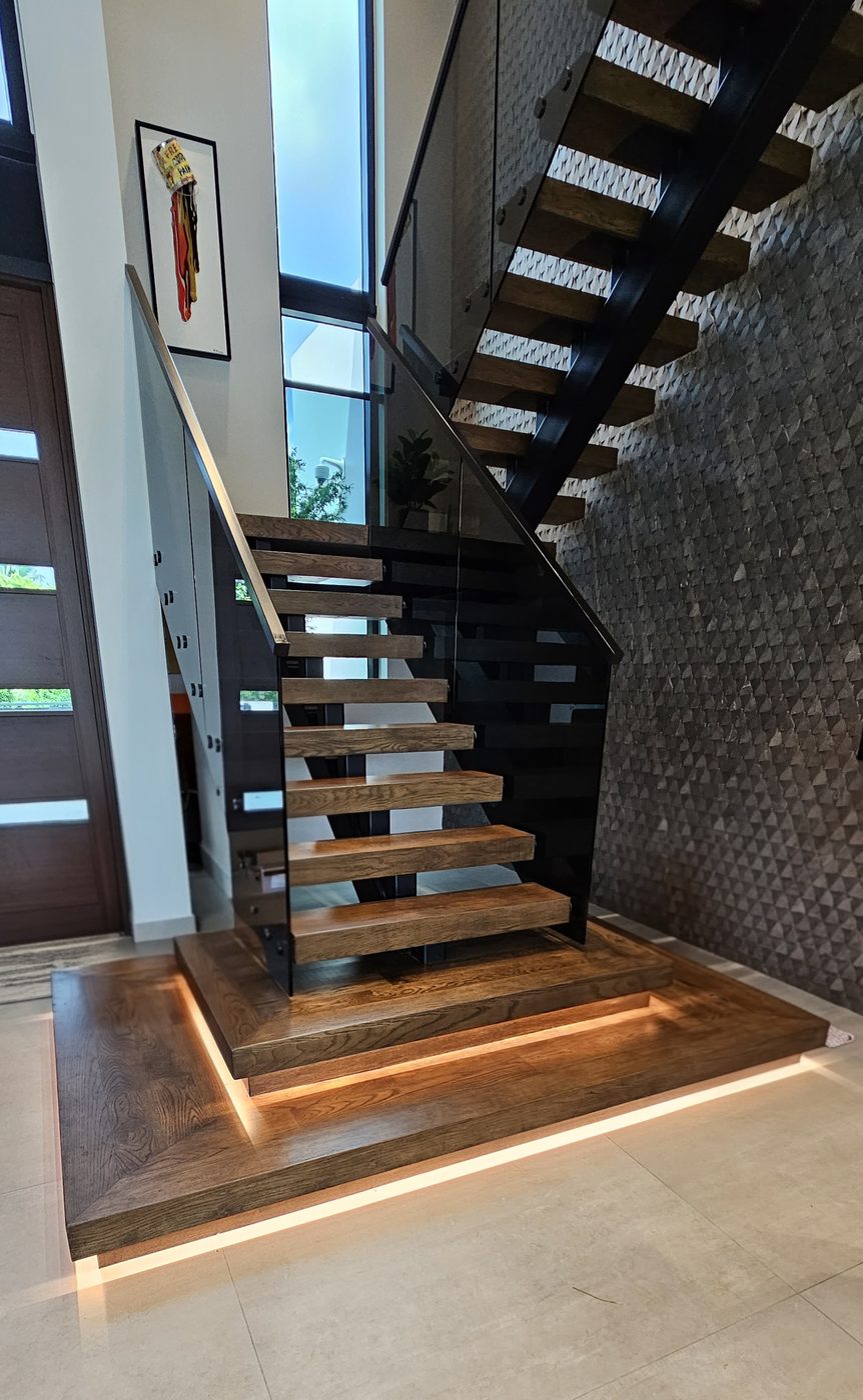 Floating staircase with smoked-glass railing and a textured stone wall