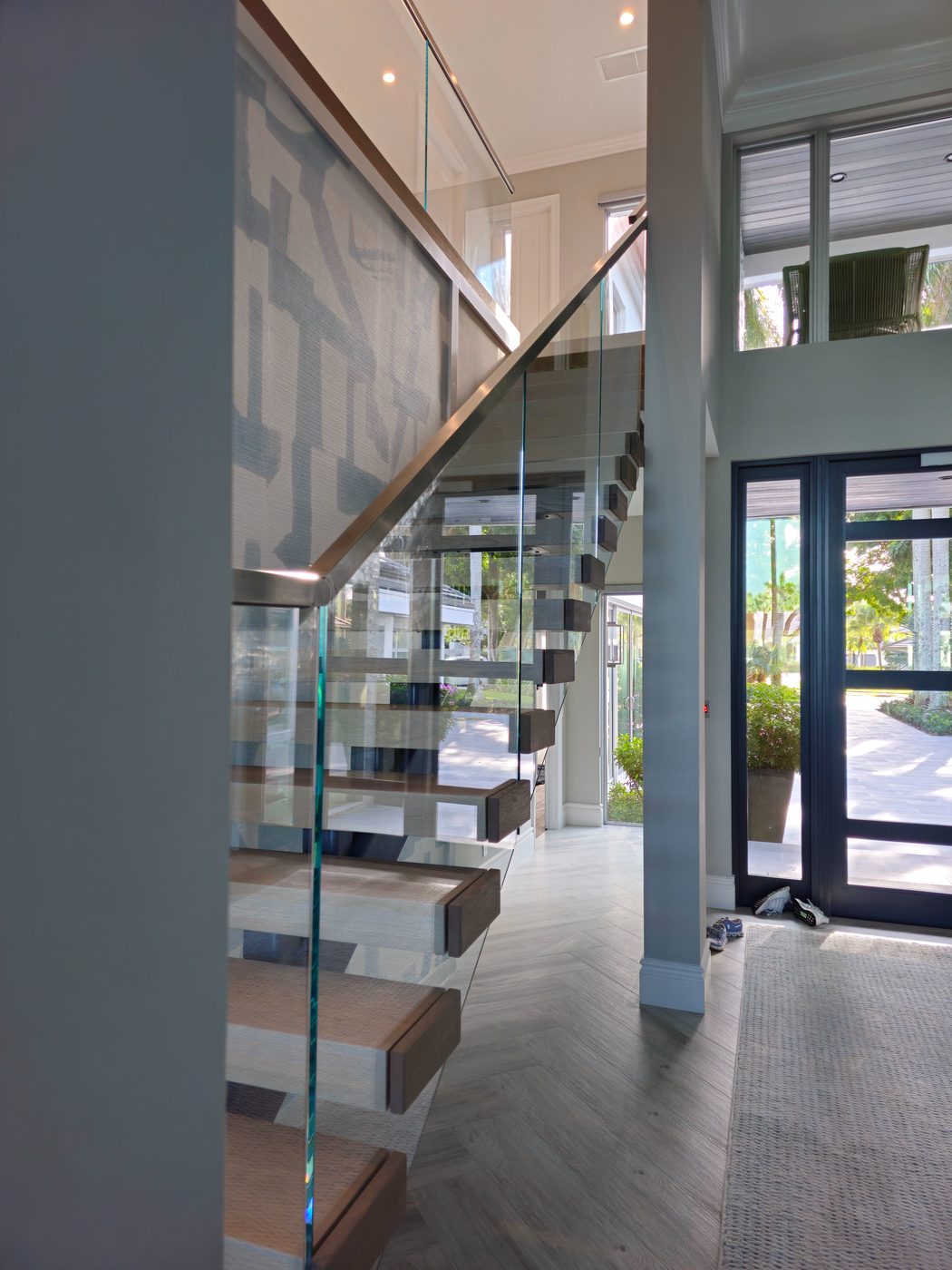 Floating staircase with frameless glass railing in a bright foyer