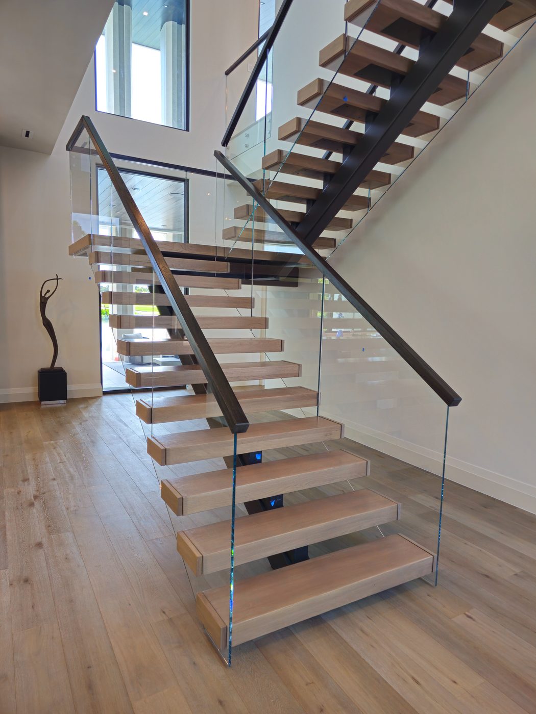 Floating wood-tread staircase with frameless glass railing