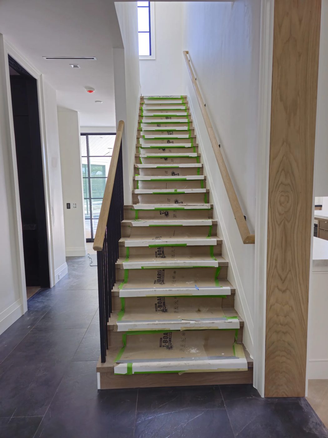 Staircase with black rod balusters and oak handrail