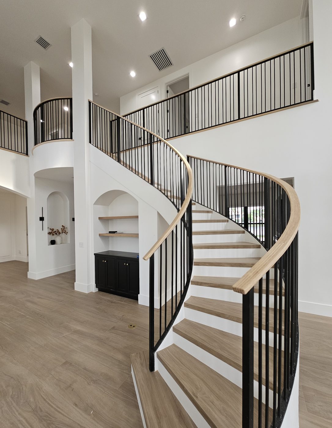 Curved staircase with iron balusters and wood handrail