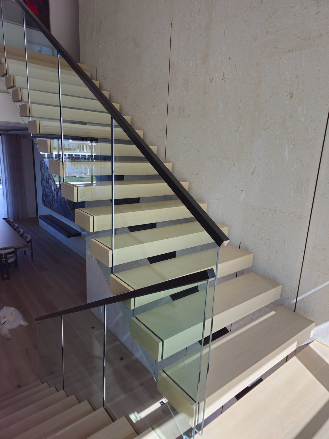 Floating staircase with frameless glass beside limestone