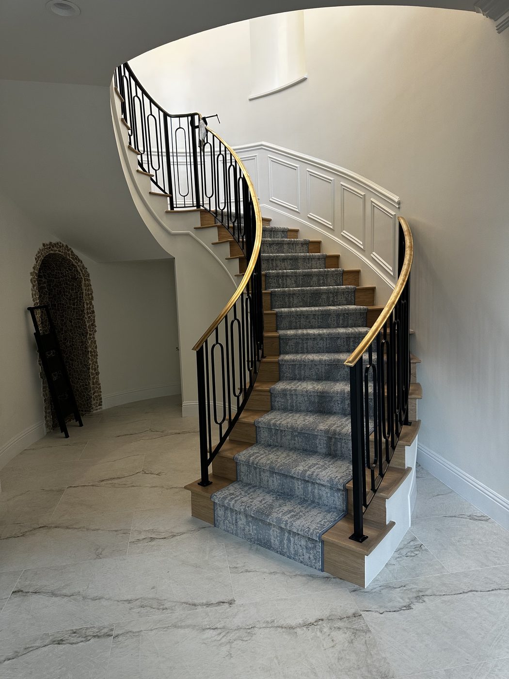 Curved staircase with iron balusters and brass handrail